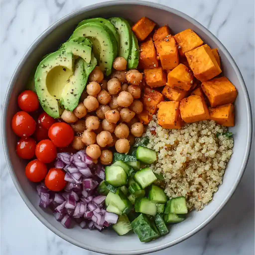 Vegan grain bowl with roasted tofu, avocado, cherry tomatoes, cucumber, chickpeas, red onion, and quinoa, drizzled with a light dressing. Nutritious, colorful, and perfect for a healthy meal.