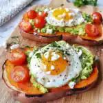 Delicious sweet potato toast topped with mashed avocado, cherry tomatoes, and a perfectly cooked sunny-side-up egg, perfect for healthy breakfast or brunch.