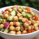 Vibrant chickpea salad with cucumbers, tomatoes, red onions, and herbs, perfect for a nutritious meal or side dish. Easy to prepare and full of flavor.