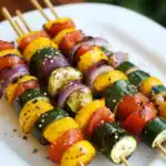 Colorful grilled vegetable skewers featuring zucchini, bell peppers, cherry tomatoes, and red onions seasoned with black pepper and herbs, perfect for barbecues and healthy meals.