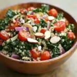 Bright, fresh vegan kale salad with cherry tomatoes, sliced almonds, red onions, quinoa, and feta cheese, dressed with lemon vinaigrette. Perfect for healthy eating and plant-based meals.