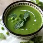 Vibrant green pea soup garnished with fresh mint leaves and peas, served in an elegant bowl. Perfect for healthy, flavorful, and easy-to-make recipes featuring fresh ingredients.