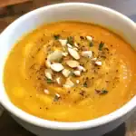 Delicious and hearty butternut squash soup garnished with toasted almonds and fresh herbs, perfect for cozy meals and healthy eating.
