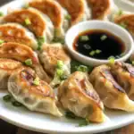 Delicious Asian dumplings with soy sauce, served with chopped green onions for added flavor and freshness. Perfect appetizer or main dish option for Asian cuisine lovers.