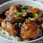 Delicious sweet soy glazed chicken served over rice, garnished with green onions and sesame seeds for a flavorful Asian-inspired meal.
