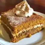 Delicious pumpkin spice cake topped with whipped cream and cocoa powder, perfect for fall desserts and gatherings. Easy to make with warm spices and moist texture.