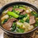 Hearty beef and vegetable soup with tender beef chunks, leafy greens, and potatoes in a clear broth. Perfect for comforting meals and easy to prepare.