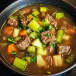 Hearty beef and vegetable soup with chunks of beef, carrots, celery, and fresh herbs in a savory broth. Perfect for a comforting meal.