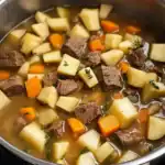 Hearty beef stew with potatoes, carrots, and herbs in a savory broth, perfect for comforting meals.