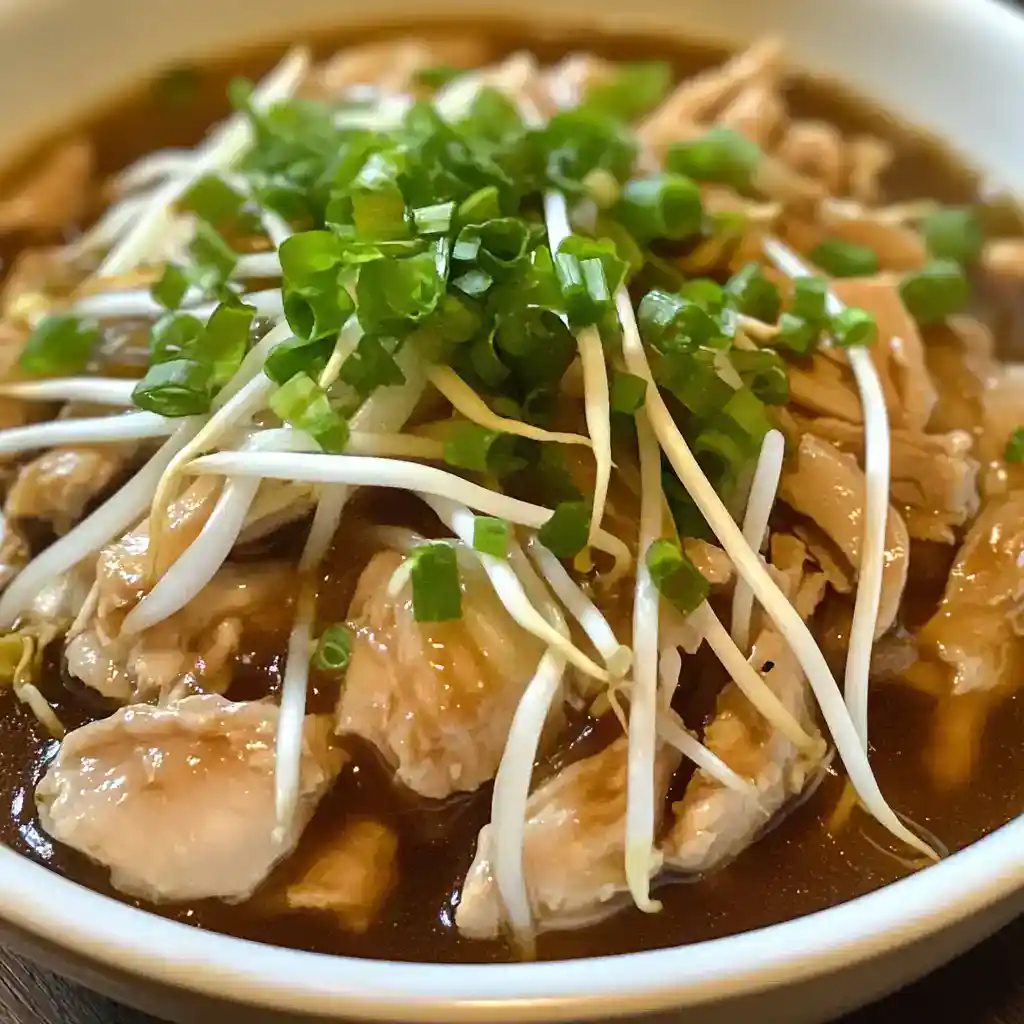 Delicious chicken stir-fry with bean sprouts, green onions, and savory sauce in a white bowl, showcasing a healthy Asian-inspired dish.
