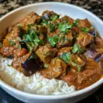 Delicious beef and eggplant curry served over fluffy white rice, garnished with fresh cilantro, perfect for a hearty and flavorful meal.