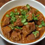 Delicious beef stew cooked in rich, flavorful sauce garnished with fresh cilantro. Perfect comfort food for cold days or hearty meals.