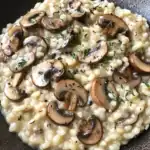 Delicious creamy mushroom risotto garnished with fresh herbs, perfect for a comforting meal.