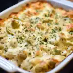 Delicious baked artichoke pasta casserole topped with melted cheese and herbs, perfect for a comforting family dinner or special occasion.