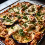 Delicious baked eggplant parmesan with melted cheese, fresh herbs, and tomato sauce, perfect for a hearty vegetarian meal.