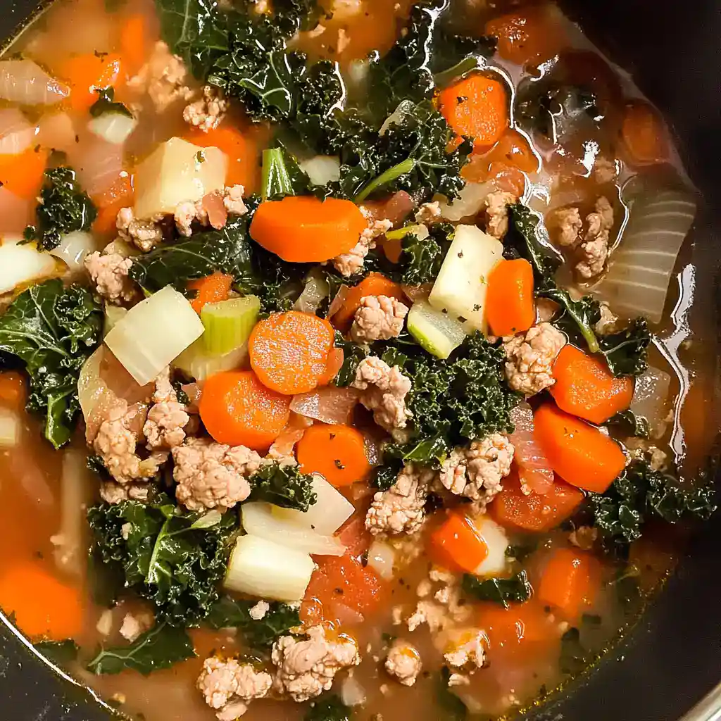 A hearty vegetable and ground meat soup with carrots, kale, and celery in a savory broth. Perfect for a nutritious, comforting meal.