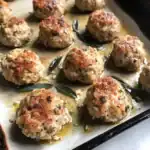 Delicious homemade meatballs cooked with fresh sage and garlic, served on a baking sheet with flavorful juices. Perfect for appetizers or family dinners.