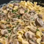 Close-up of creamy mushroom pasta garnished with parsley, showcasing tender mushrooms and pasta in a rich sauce.