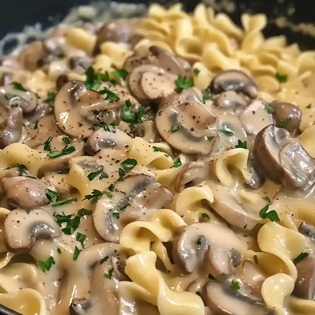 Close-up of creamy mushroom pasta garnished with parsley, showcasing tender mushrooms and pasta in a rich sauce.